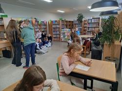 Uczniowie podczas Dnia Głośnego Czytania 2022 w bibliotece.